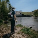 a man with a backpack on a bicycle by a river